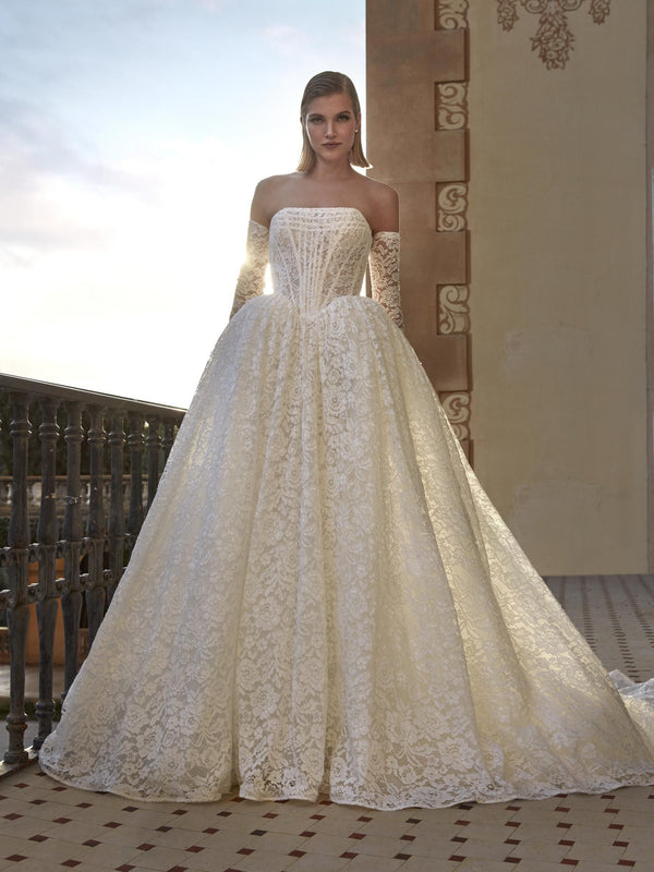 Woman wearing a white lace wedding dress on a balcony, Pronovias Beatris