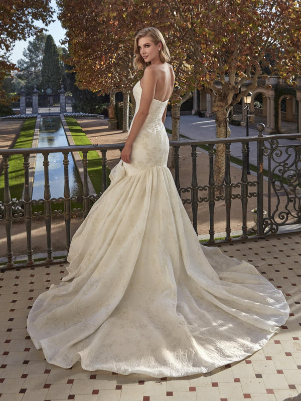 Woman in a white wedding dress by Pronovias BEEGOLD standing on a balcony with a scenic background