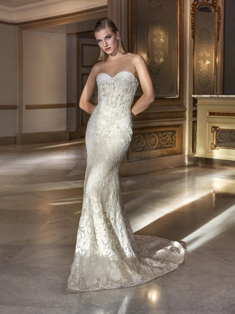 Woman wearing a white lace wedding dress by Pronovias HYAM  in an elegant room.