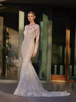 Woman in a lace wedding dress by Pronovias ILA standing in front of a modern building entrance.