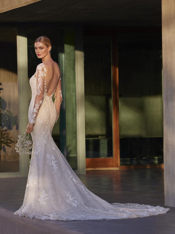 Woman in a lace wedding dress by Pronovias ILA standing in front of a modern building entrance.
