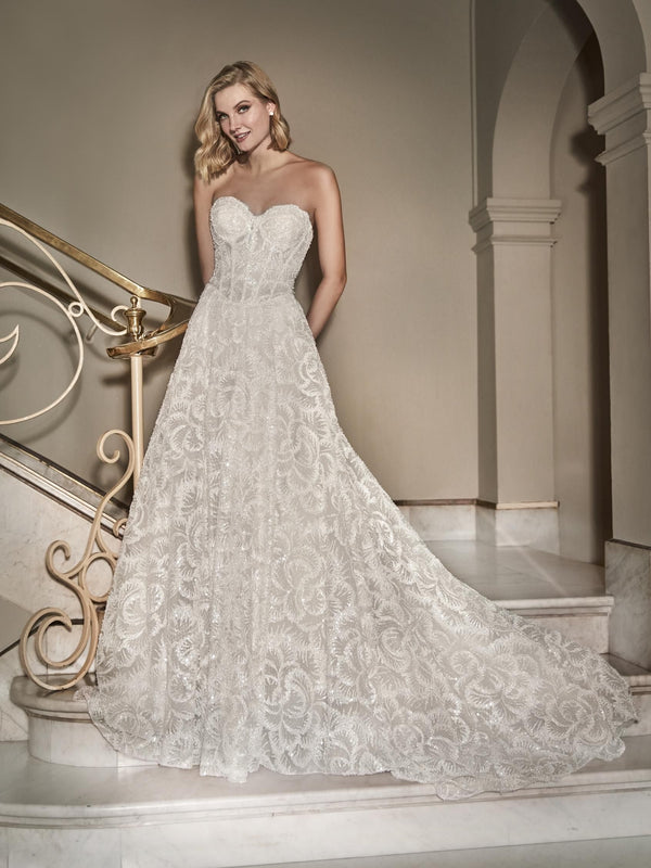 Woman in a white lace wedding dress  by Pronovias STARLEE standing on a staircase