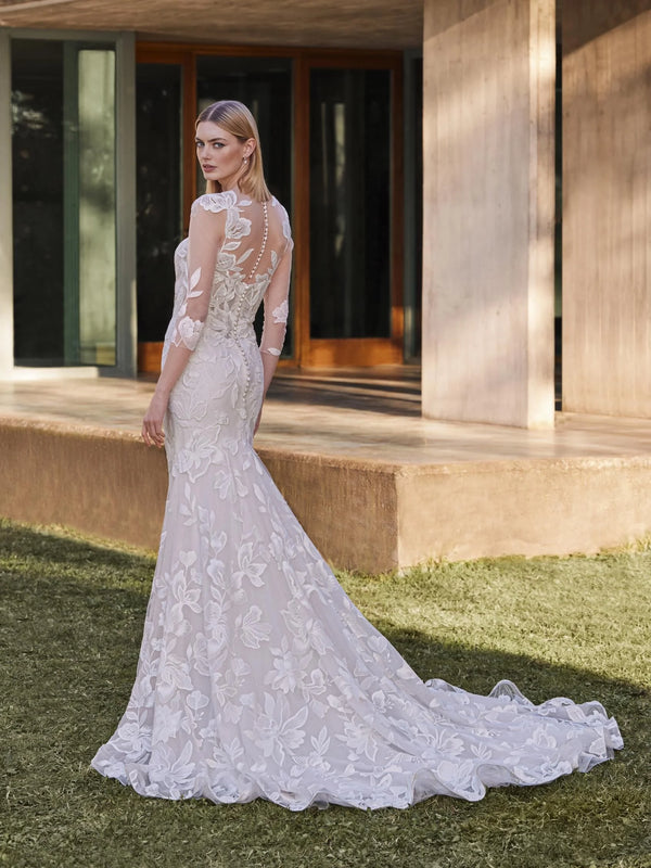 Woman in a white lace wedding dress by Pronovias YAI standing outdoors.