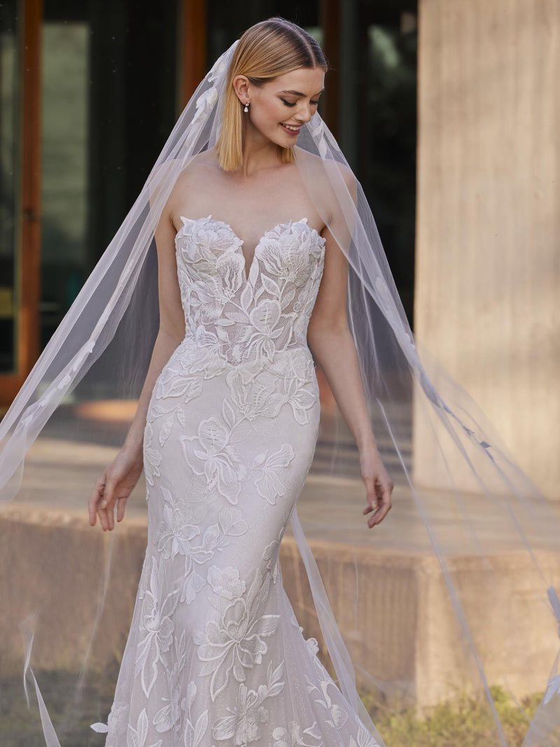 Woman wearing a white lace wedding dress by Pronovias YAI with a long veil.
