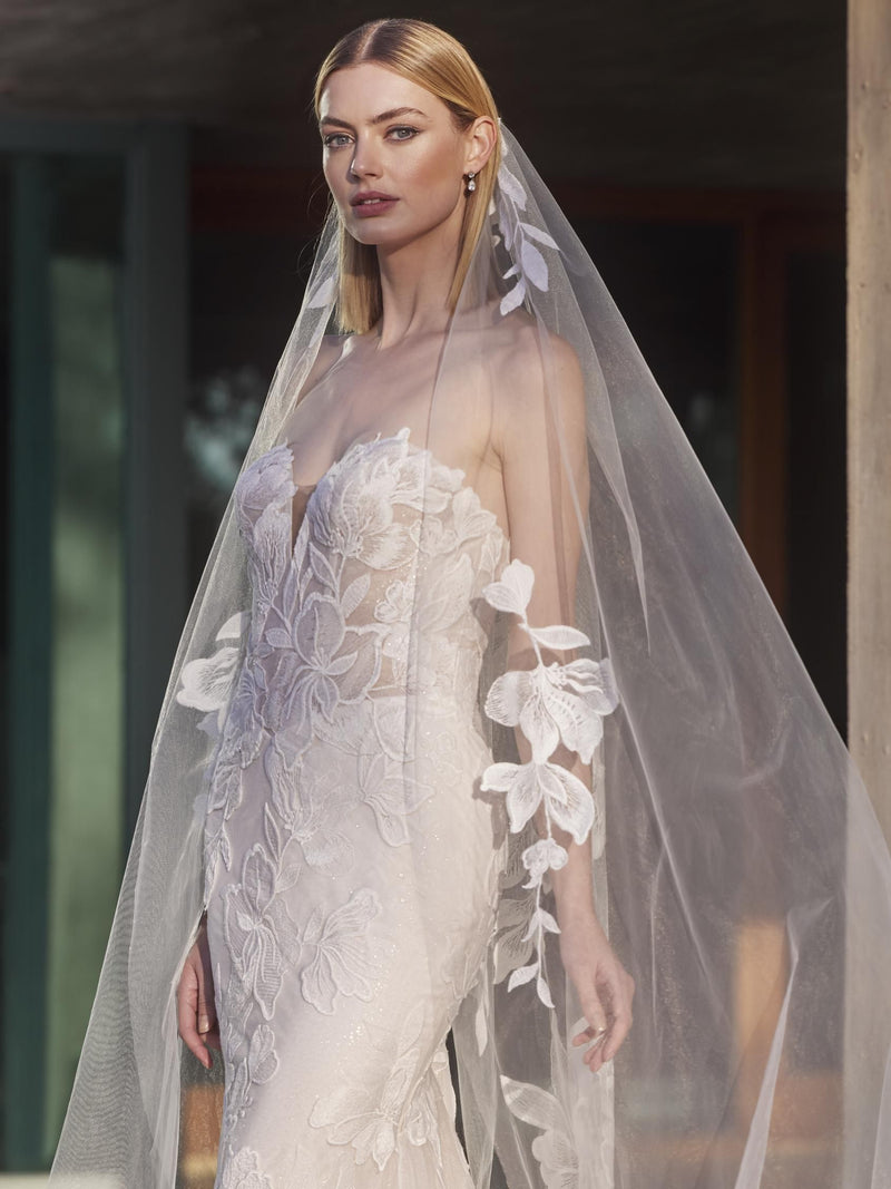 Model wearing a wedding dress with floral details and a veil by Pronovias YAI